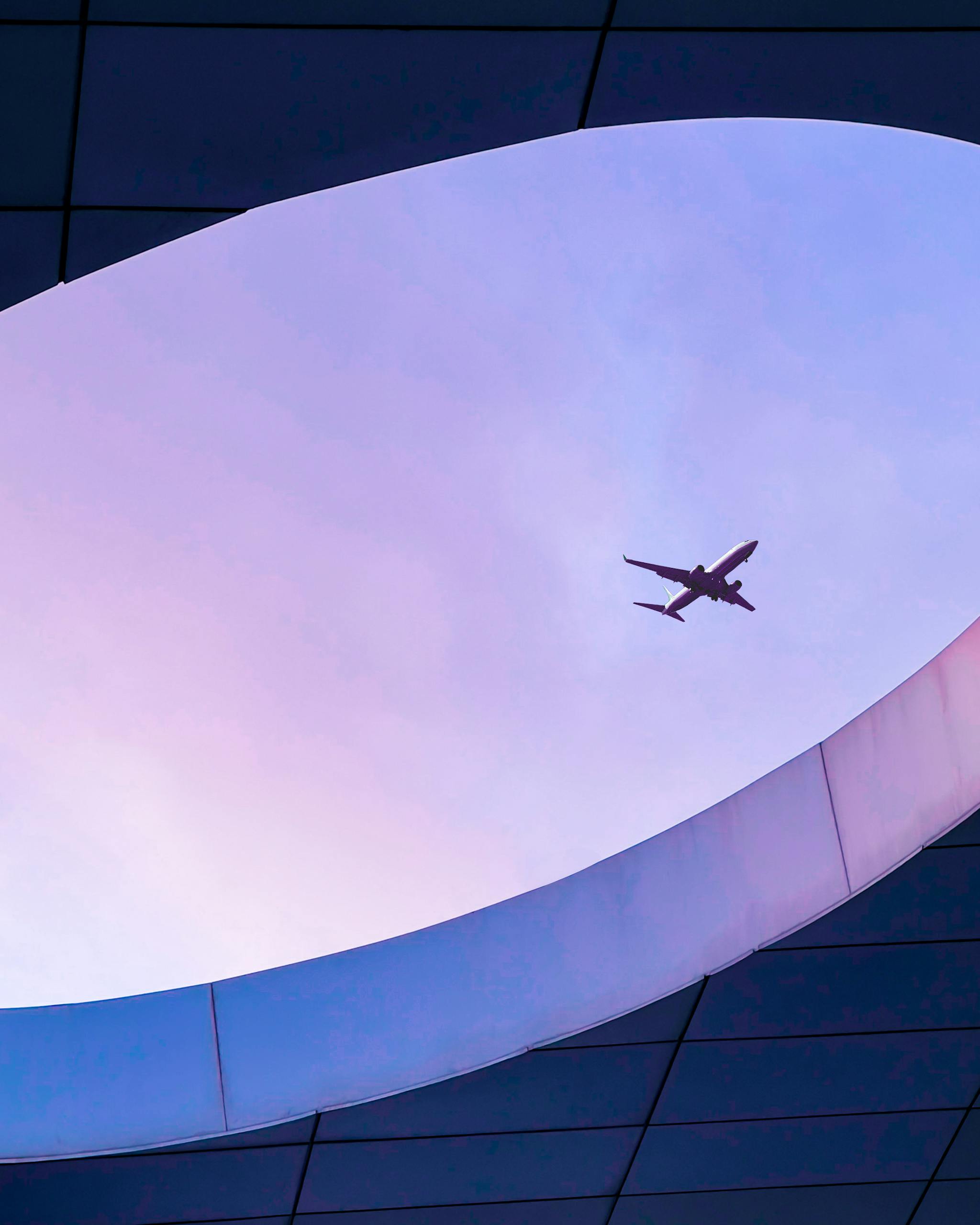 A sleek airplane flies over modern architectural structure in Casablanca, Morocco.